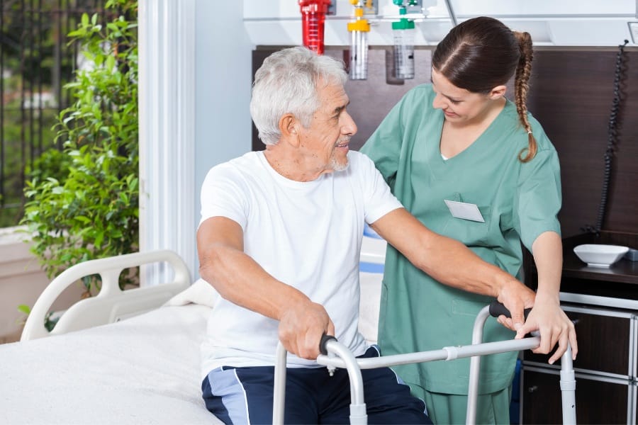 An RN in a long-term care facility assisting her patient with mobility