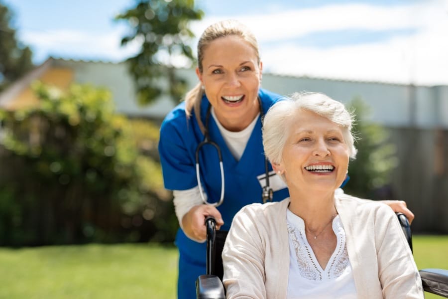 Smiling private duty nurse and her elderly patient in a wheelchair