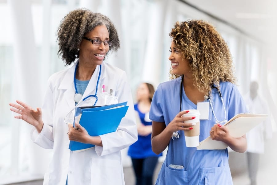 Two smiling nurses walking in a healthcare facility