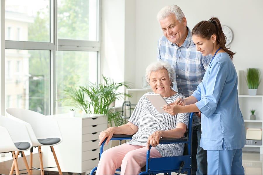 A woman with Parkinson's Disease sitting with her husband and private nurse