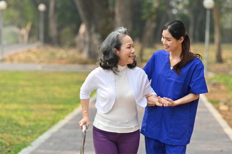 RN walking outside with her elderly patient