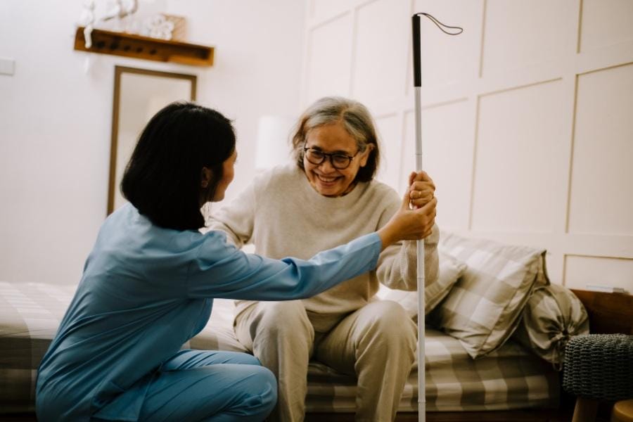 Private duty nurse helping elderly client get out of bed