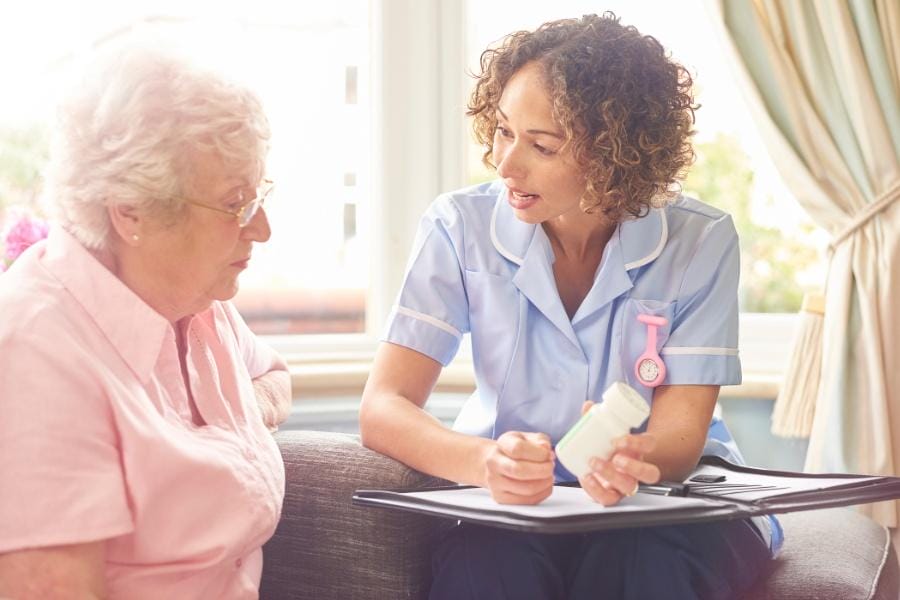 An RN assisting her elderly client with pill organization