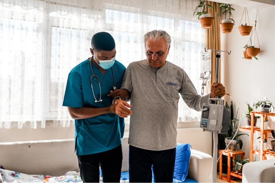 Private nurse assisting with a patient with IV infusion after surgery