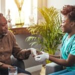 at home nurse assisting her patient with Parkinson's Disease