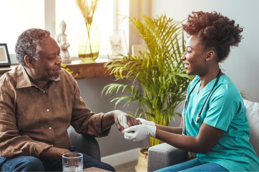 at home nurse assisting her patient with Parkinson's Disease