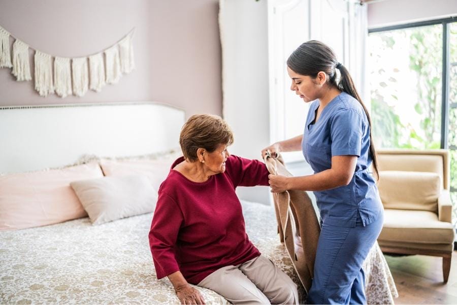 Home nurse helping her PD patient get dressed