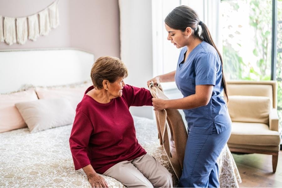 after surgery care nurse assisting her client getting dressed